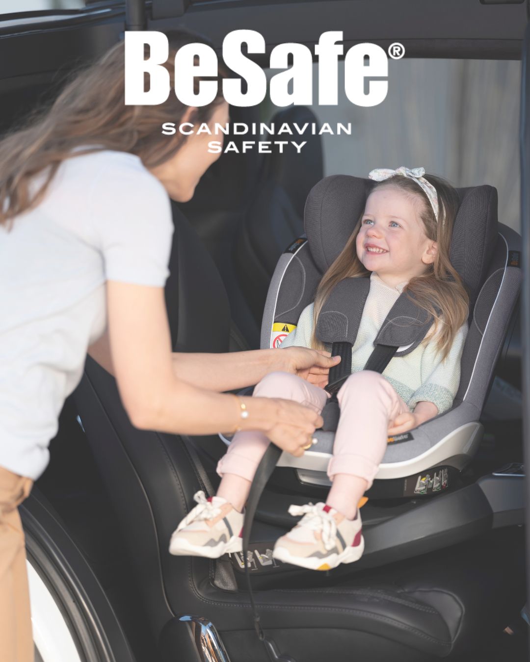 mama abrochando el cinturon a su hija de 4 a&ntilde;os que viaja en una silla a contramarcha Besafe