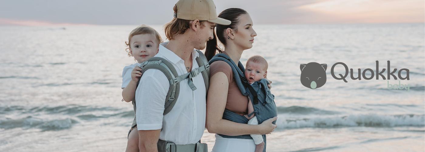 papa porteando en la espalda y mama porteando delante en portabebes ergon&oacute;micos y evolutivos de la marca quokkababy